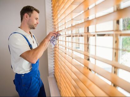 Picture of a handyman cleaning wooden blinds