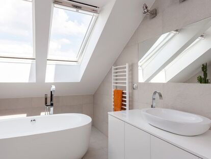 Picture of an updated white bathroom with 2 large skylights over a tub
